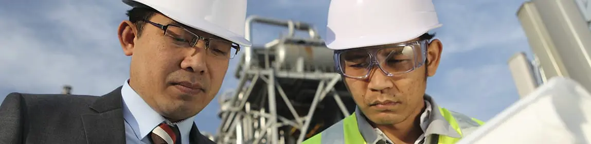 Manager and workman discussing a project in front of a refinery